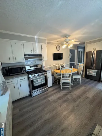 a kitchen with stainless steel appliances wooden floor and a view of living room