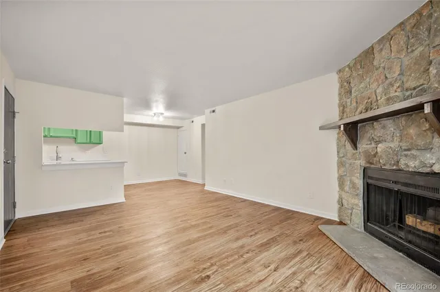 a view of empty room with wooden floor and fireplace