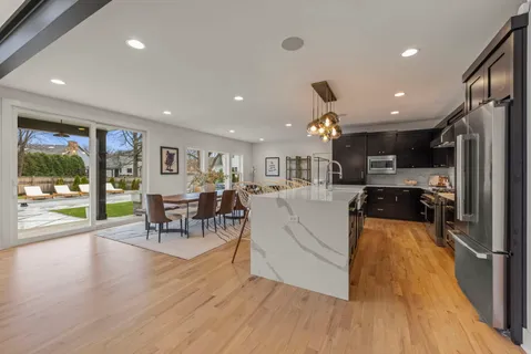 a living room with stainless steel appliances kitchen island granite countertop furniture wooden floor and a kitchen view
