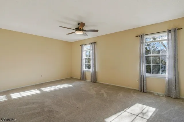 a view of an empty room with cabinet and a ceiling fan