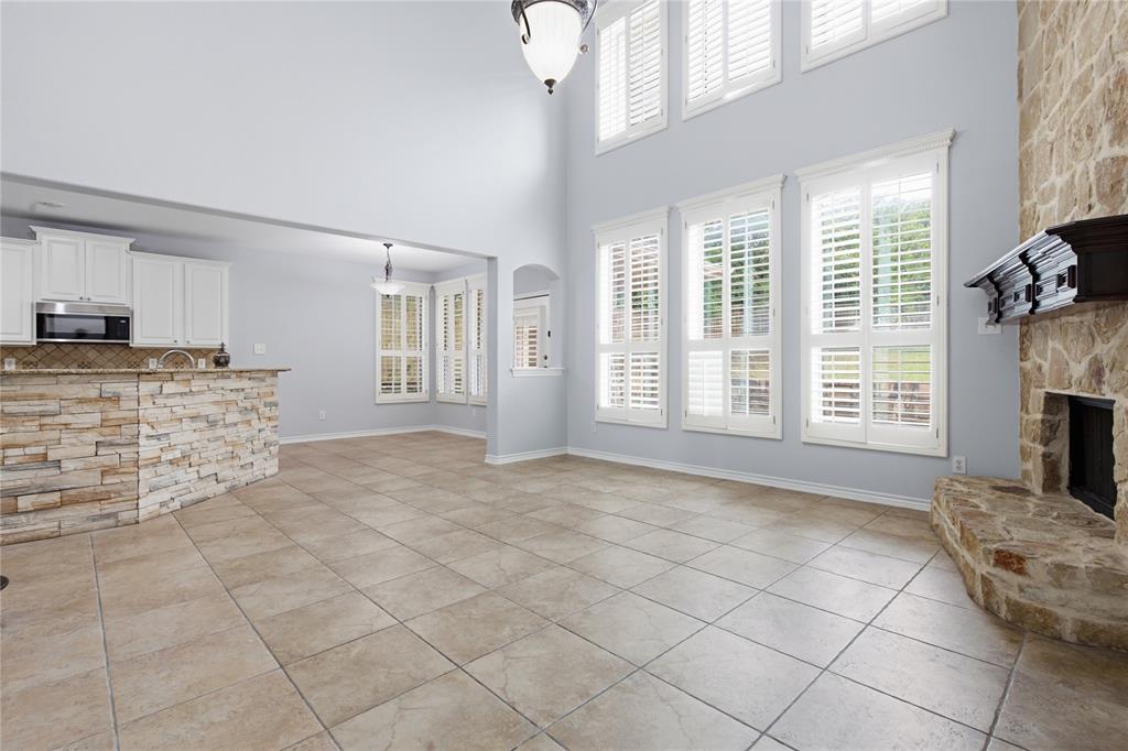 10001 Thurman Road Fort Worth, TX 76244 - Photo 10 of 40 Two-story living area featuring tile flooring and a stone-clad fireplace with a dark wood mantel