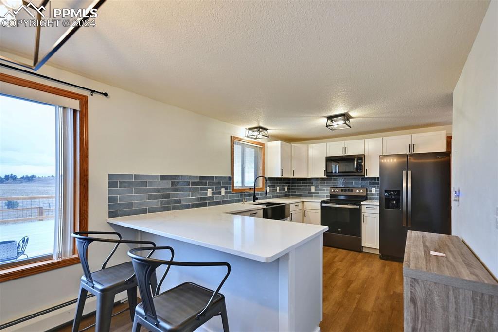 899 Concho Trail Hartsel, CO 80449 - Photo 3 of 27 a kitchen with stainless steel appliances a stove a refrigerator a sink dishwasher a dining table and chairs with wooden floor