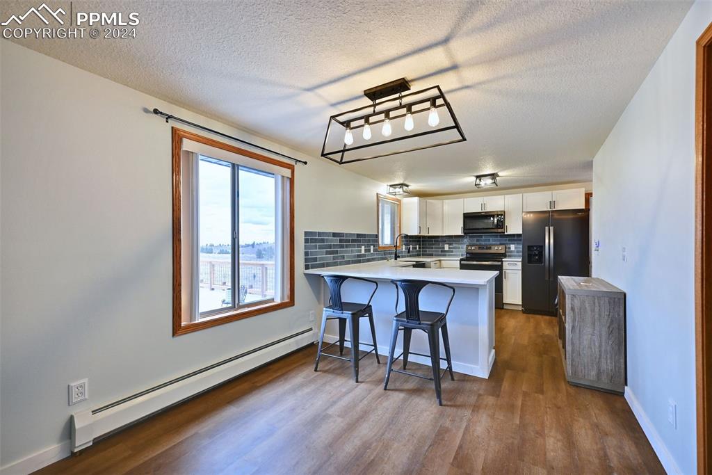 899 Concho Trail Hartsel, CO 80449 - Photo 10 of 27 a view of kitchen with stainless steel appliances granite countertop a stove a refrigerator a sink a dining table and chairs with wooden floor