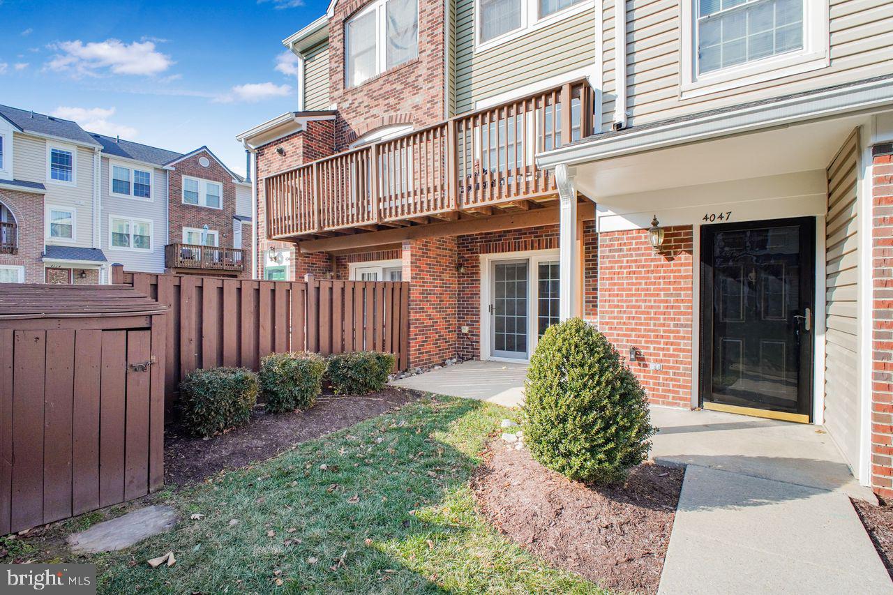 4047 Chetham Way Woodbridge, VA 22192 - Photo 2 of 55 a view of a brick house with many windows plants and wooden fence