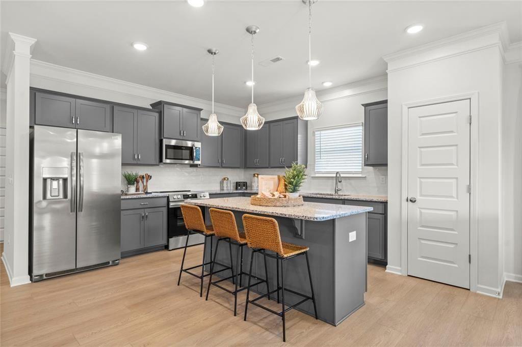 105 Alcovy Trail Calhoun, GA 30701 - Photo 11 of 28 a kitchen with stainless steel appliances kitchen island granite countertop a table chairs sink and cabinets