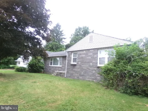 a brick house with a small yard and large trees