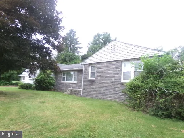 a brick house with a small yard and large trees