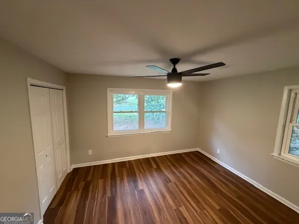 a view of empty room with wooden floor and fan