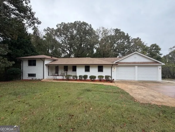a front view of a house with a garden and trees