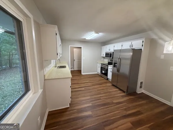 a view of an empty room with wooden floor and a window