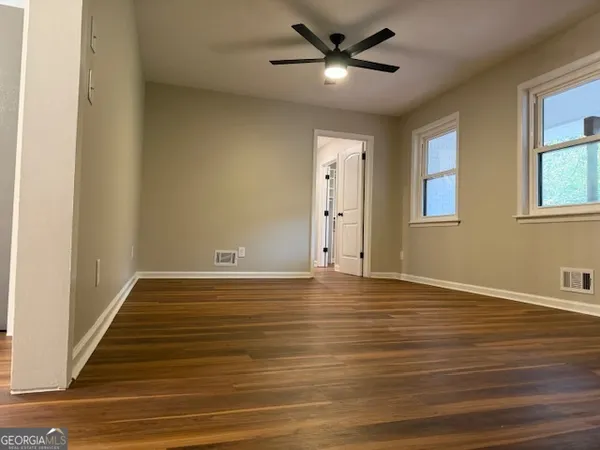 a view of a hallway with wooden floor and a bathroom