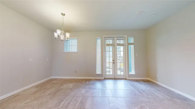 an empty room with chandelier fan and windows