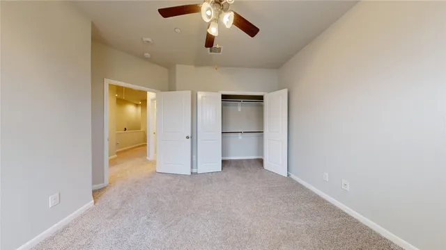 an empty room with closet and a chandelier fan