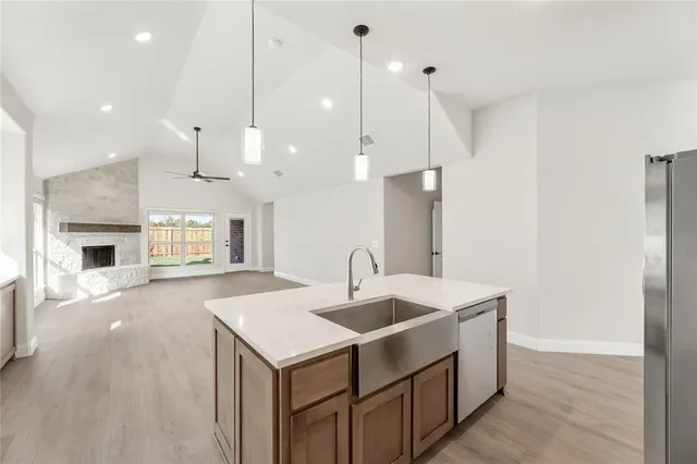 a kitchen with kitchen island a sink stainless steel appliances and a fireplace