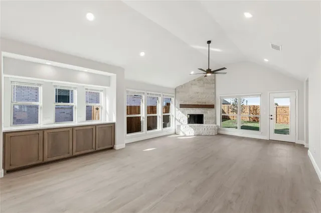 an empty room with wooden floor fireplace and windows