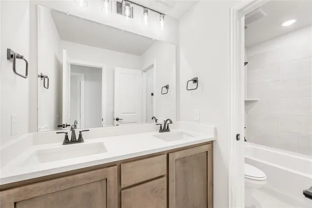 a bathroom with a sink a toilet a shower and a mirror