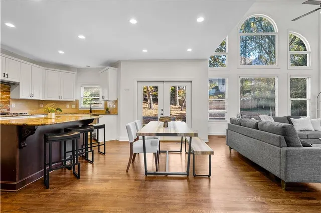 a living room with stainless steel appliances granite countertop a couch a dining table and chairs with wooden floor