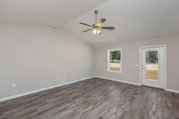 an empty room with wooden floor fan and windows