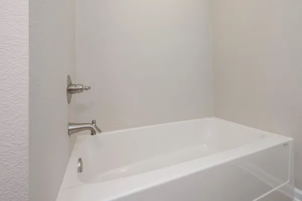 a white bath tub sitting next to a white wall