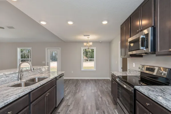 a kitchen with granite countertop stainless steel appliances a sink window and cabinets