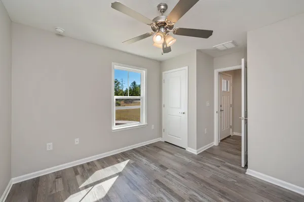 a view of an empty room with a window and wooden floor