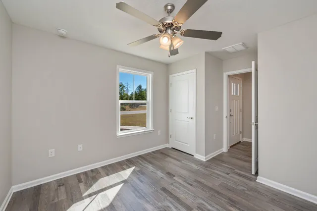 a view of an empty room with a window and wooden floor