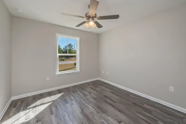 a view of room with window ceiling fan and hardwood floor