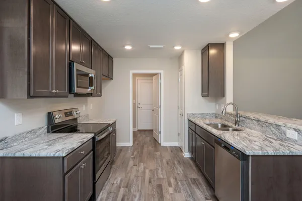 a kitchen with granite countertop stainless steel appliances sink stove microwave and cabinets