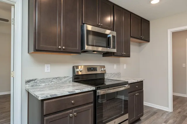 a kitchen with granite countertop cabinets stainless steel appliances and wooden floor
