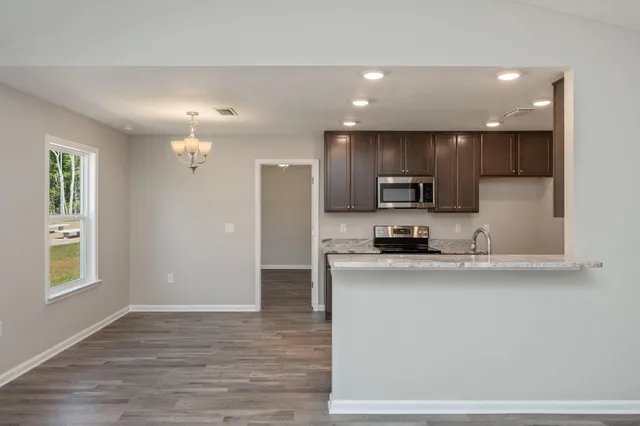 a kitchen with stainless steel appliances granite countertop a refrigerator a sink a stove and oven