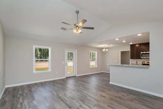 a view of an empty room with kitchen and window