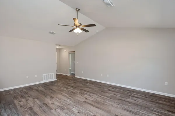 an empty room with wooden floor chandelier fan and closet area