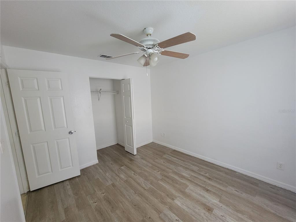 15755 Southwest 33rd Ave Road, Unit 1 Ocala, FL 34473 - Photo 6 of 9 an empty room with wooden floor and ceiling fan