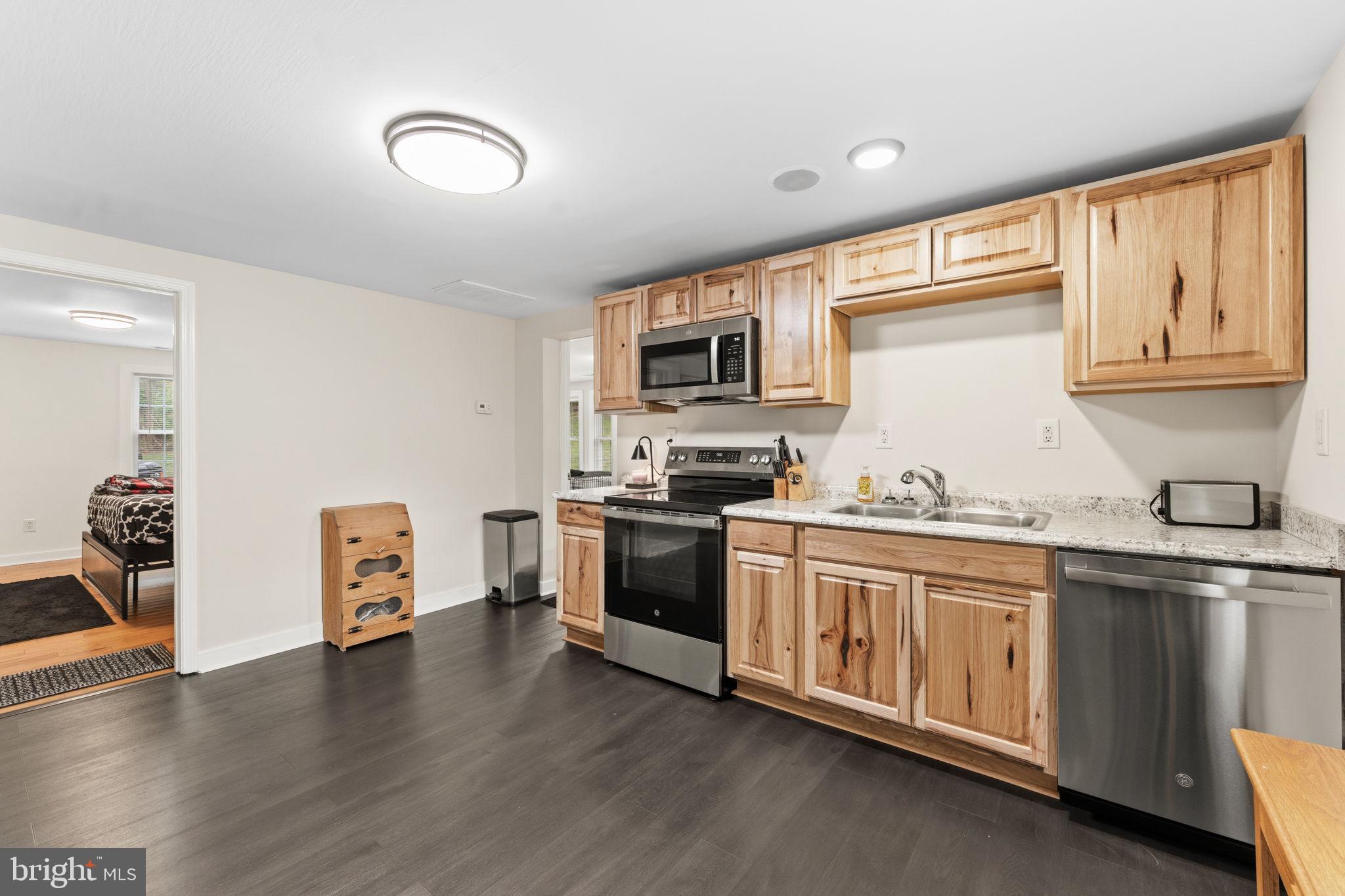 2459 Thoroughfare Road Culpeper, VA 22701 - Photo 39 of 59 a kitchen with granite countertop a stove top oven a sink dishwasher and a microwave oven with wooden floor