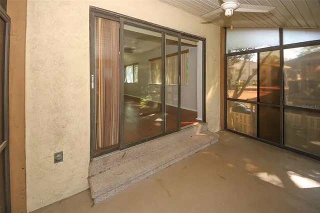 en empty room with sliding glass door and chandelier fan