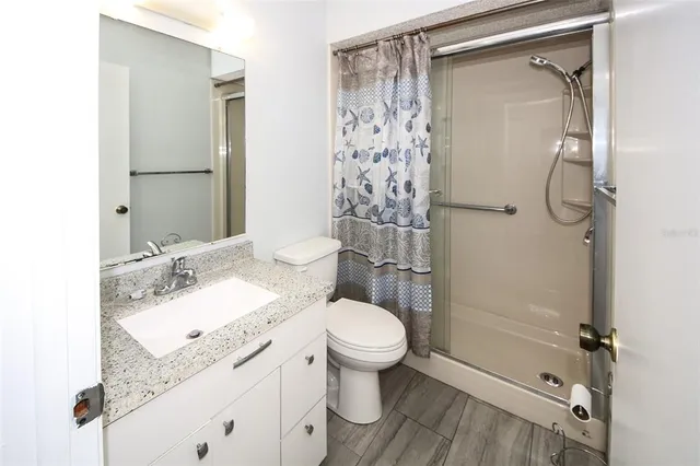 a bathroom with a granite countertop sink toilet and shower