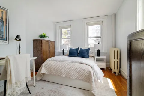 a bedroom with bed a mirror and a window