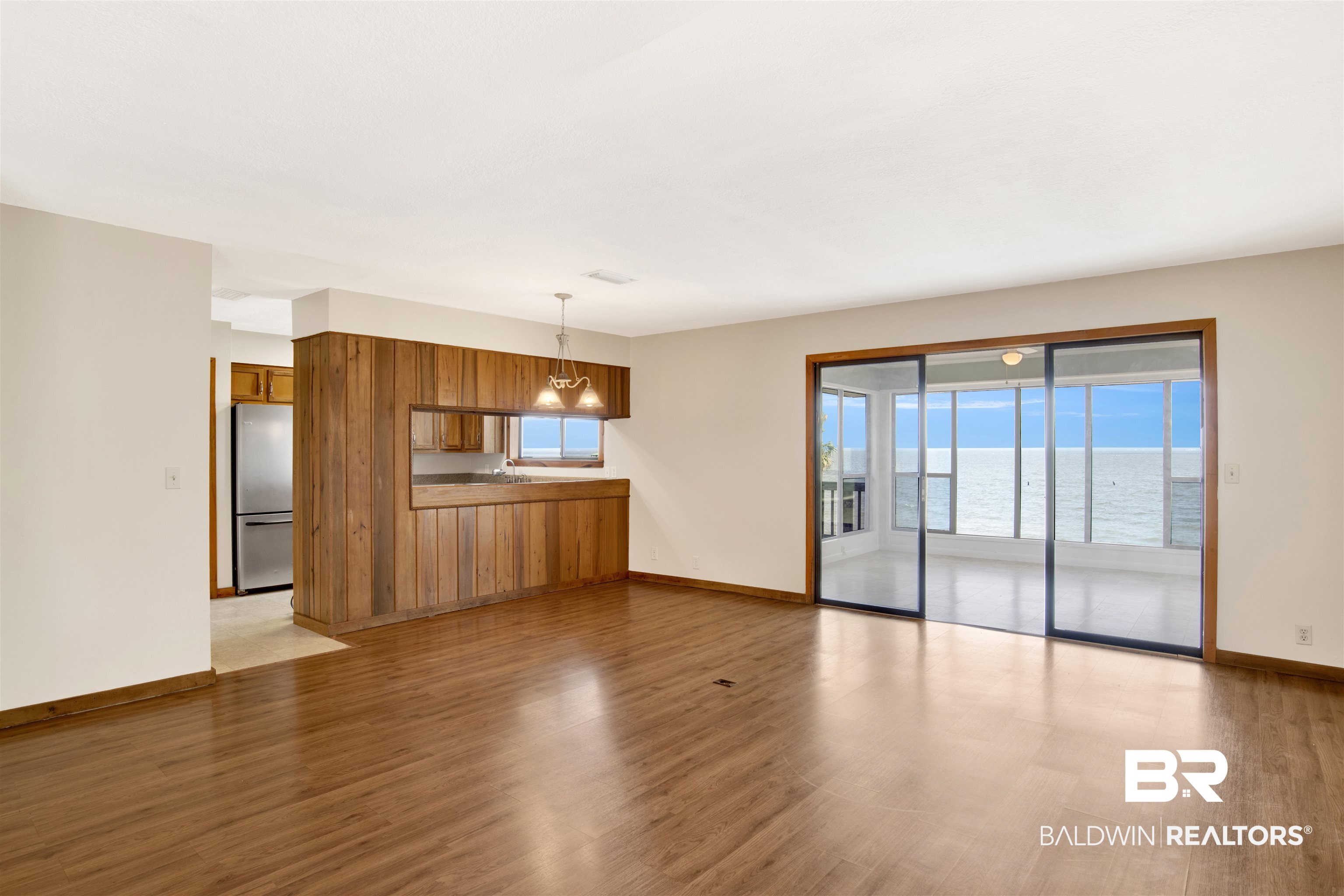 7411 Bay Road Mobile, AL 36605 - Photo 14 of 34 Unfurnished living room featuring light wood-style flooring, a water view, and a chandelier