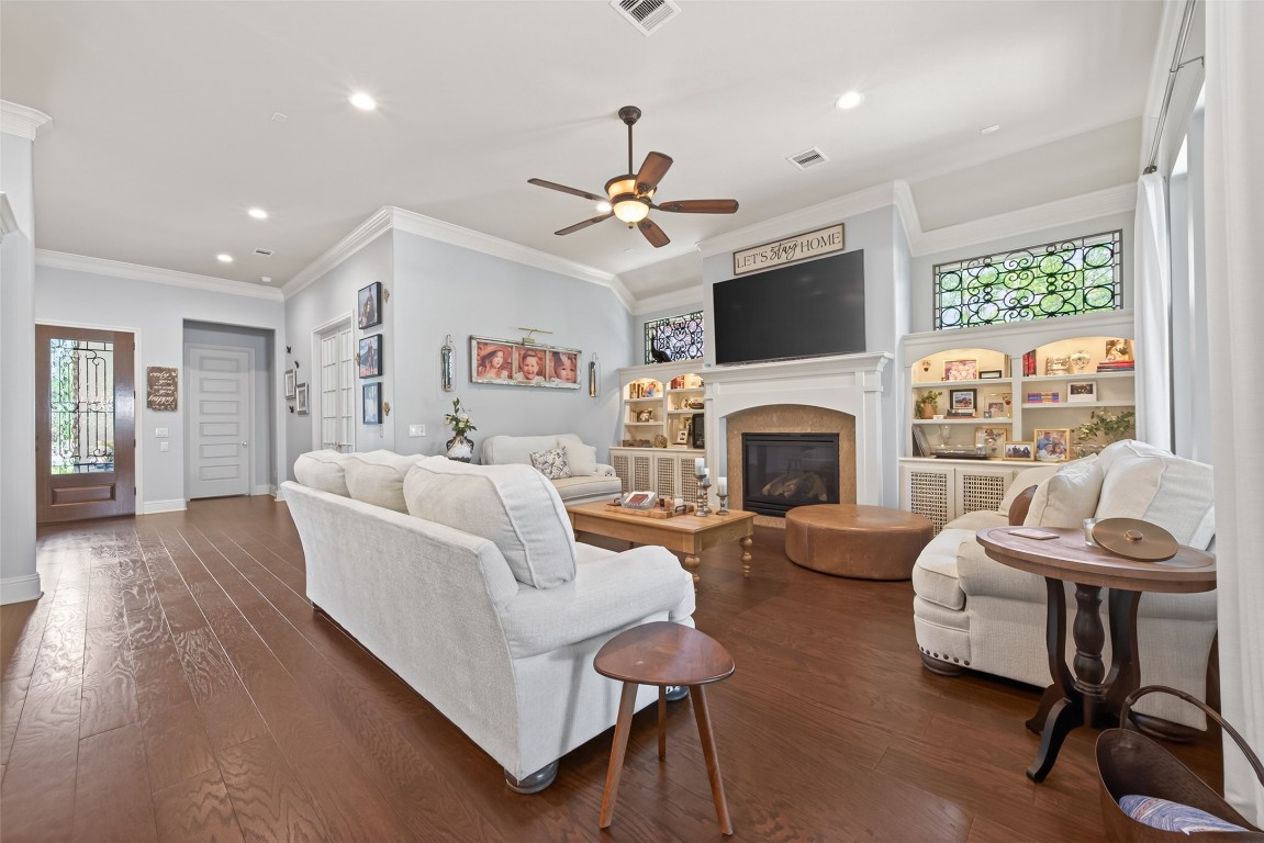 19852 Cullen Ridge Drive Porter, TX 77365 - Photo 11 of 43 The living room features hardwood floors, a cozy fireplace, and built-in shelving. It is well-lit with recessed lighting and has a ceiling fan. The open layout offers plenty of space for seating for guests and relaxation.