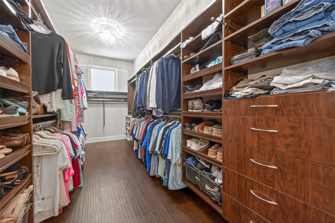 19852 Cullen Ridge Drive Porter, TX 77365 - Photo 21 of 43 Spacious Primary walk-in closet featuring wooden shelving and drawers, ample hanging space, and a shoe rack. The room is well-lit with a modern ceiling light and has a window for natural light, offering plenty of organized storage.