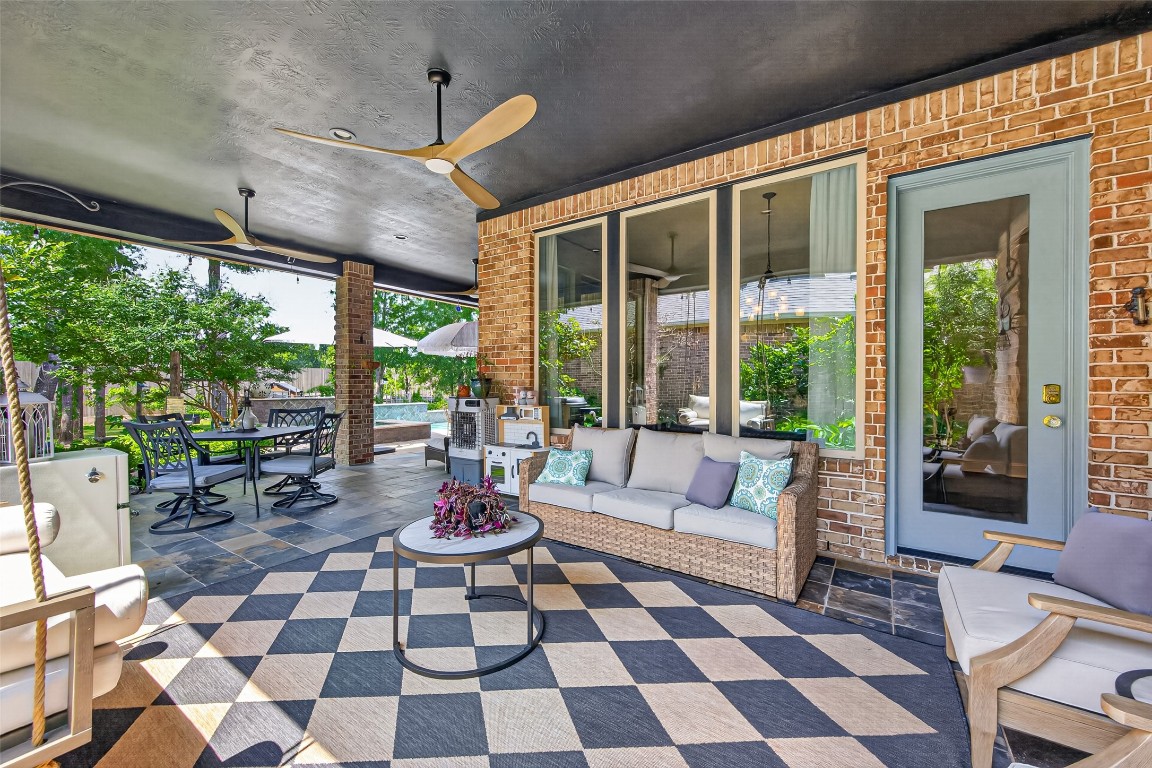 19852 Cullen Ridge Drive Porter, TX 77365 - Photo 26 of 43 This HUGE inviting back patio features elegant brick walls, stylish ceiling fans, and comfortable seating areas. The space is adorned with potted plants and decorative elements, providing a cozy atmosphere perfect for relaxation or entertaining.