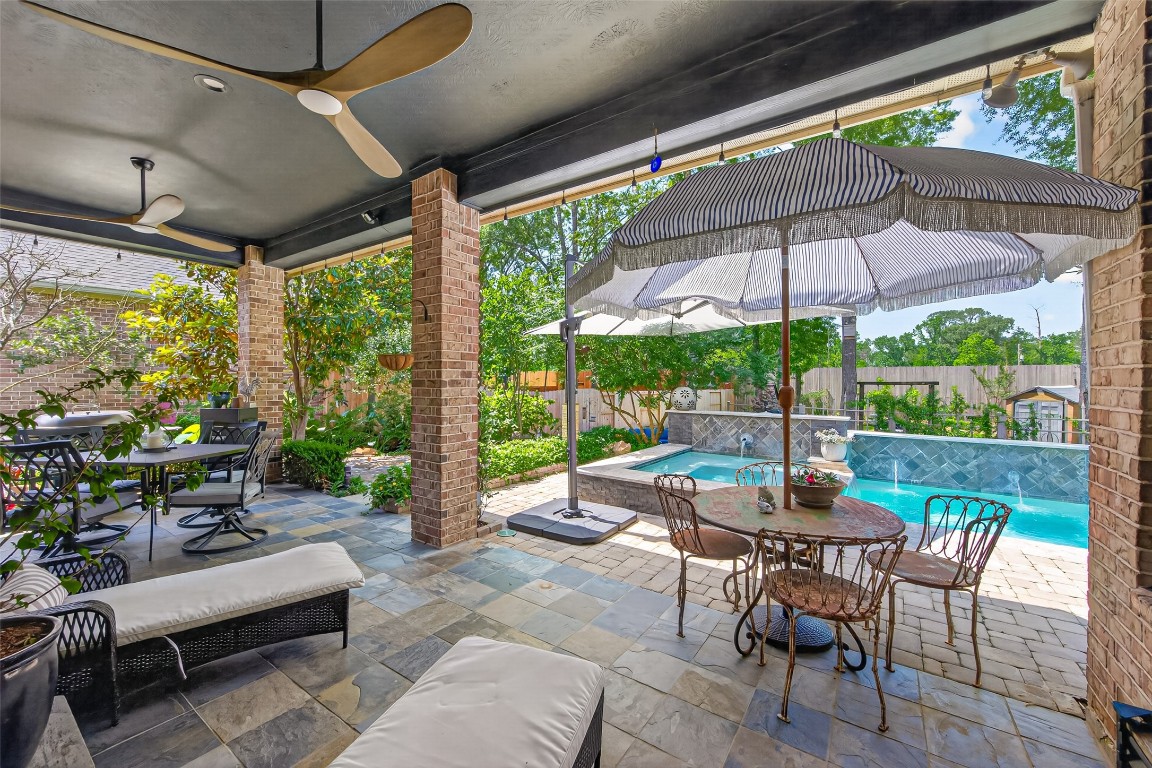 19852 Cullen Ridge Drive Porter, TX 77365 - Photo 28 of 43 Beautiful outdoor patio with a shaded seating area, modern ceiling fans for comfort, and a view of the backyard oasis and tiled pool/Hot tub surrounded by lush greenery. Perfect for relaxing and entertaining.