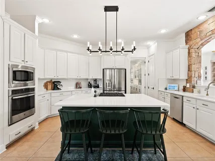 a bedroom with a bed chandelier and dresser