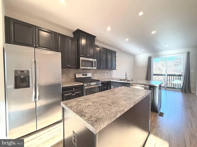 a kitchen with granite countertop a refrigerator and wooden cabinets