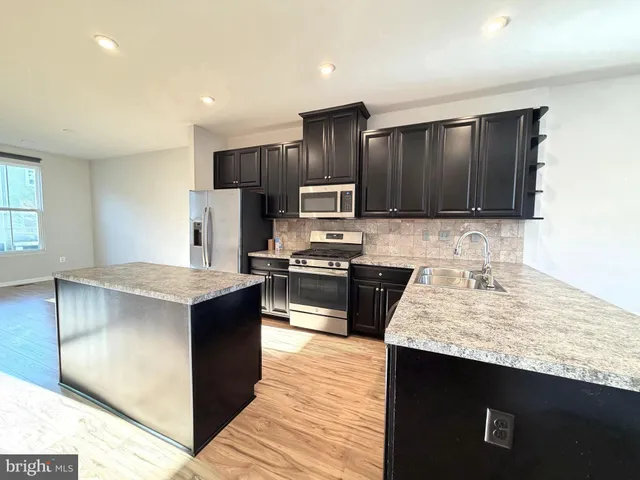 a kitchen with stainless steel appliances granite countertop a stove a sink and a refrigerator
