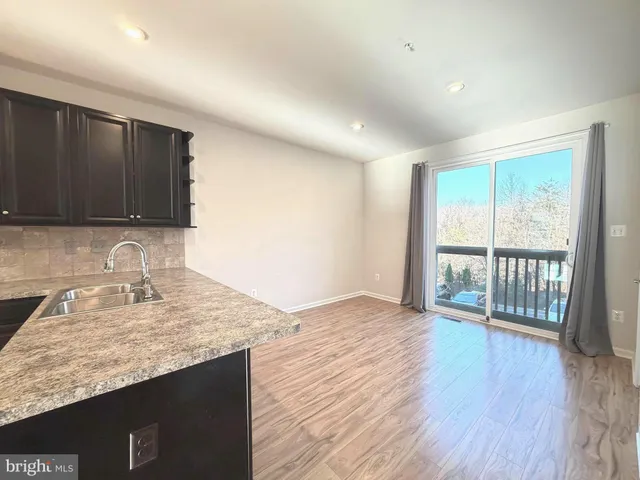 a kitchen with granite countertop wooden floors a sink and cabinets