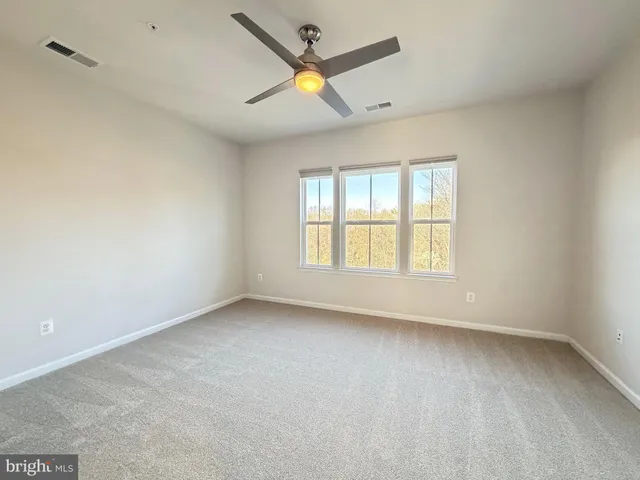 an empty room with a window and a fan