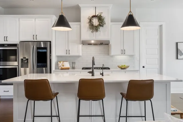 a kitchen with stainless steel appliances a dining table chairs and a refrigerator