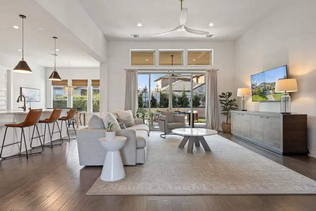 a living room with furniture large window and wooden floor