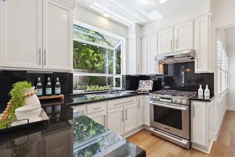 a kitchen with stainless steel appliances granite countertop a stove a sink dishwasher and cabinets with wooden floor